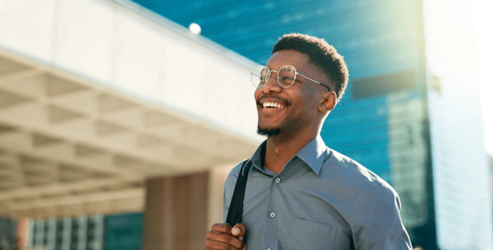 A man with glasses smiling and holding his purse.
