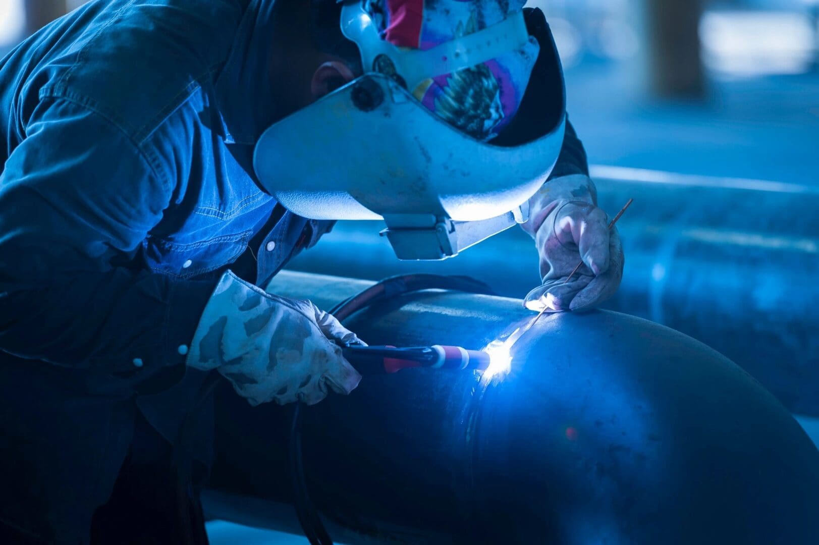 A person welding in the dark with blue light.