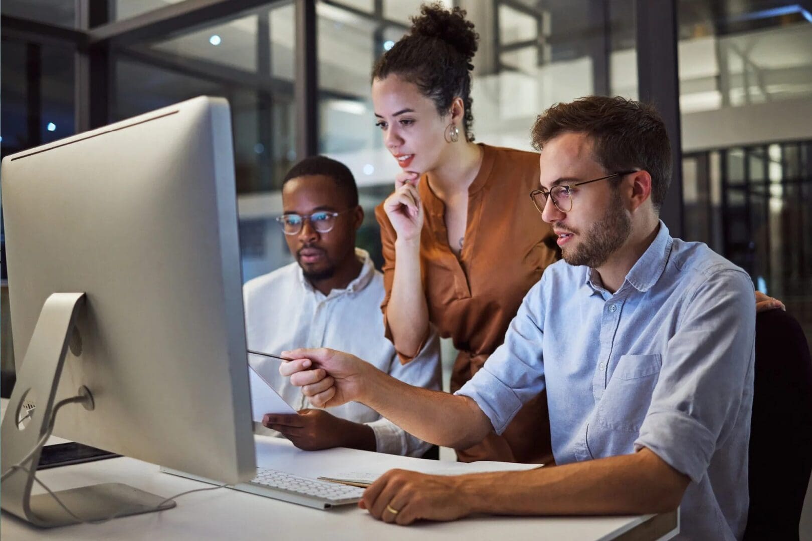 Three people are sitting at a table looking at the computer.