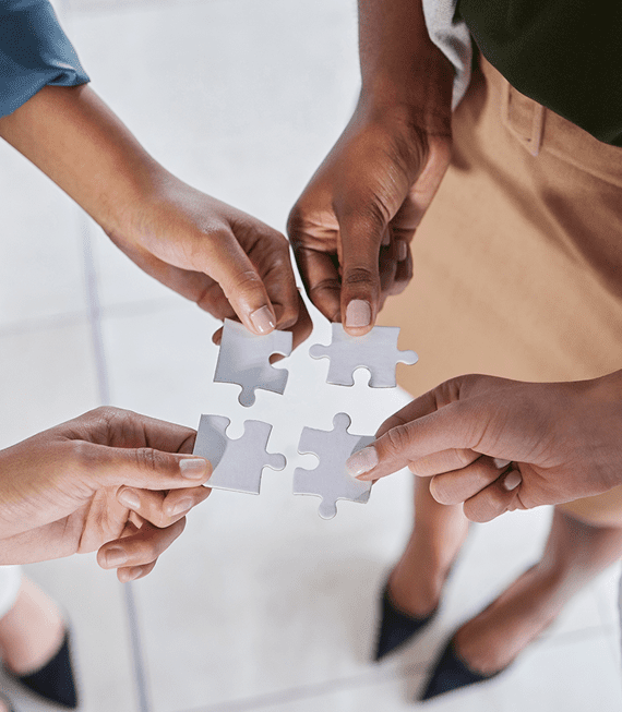 A group of people holding puzzle pieces in their hands.