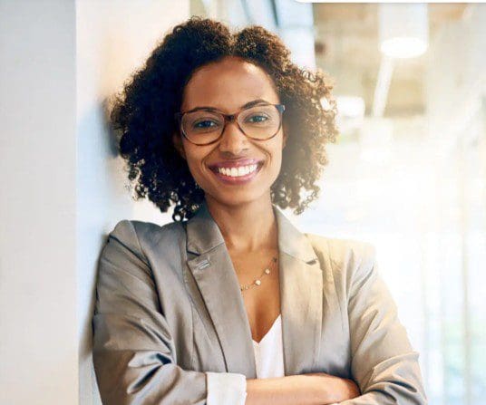 A woman with glasses standing in front of a wall.